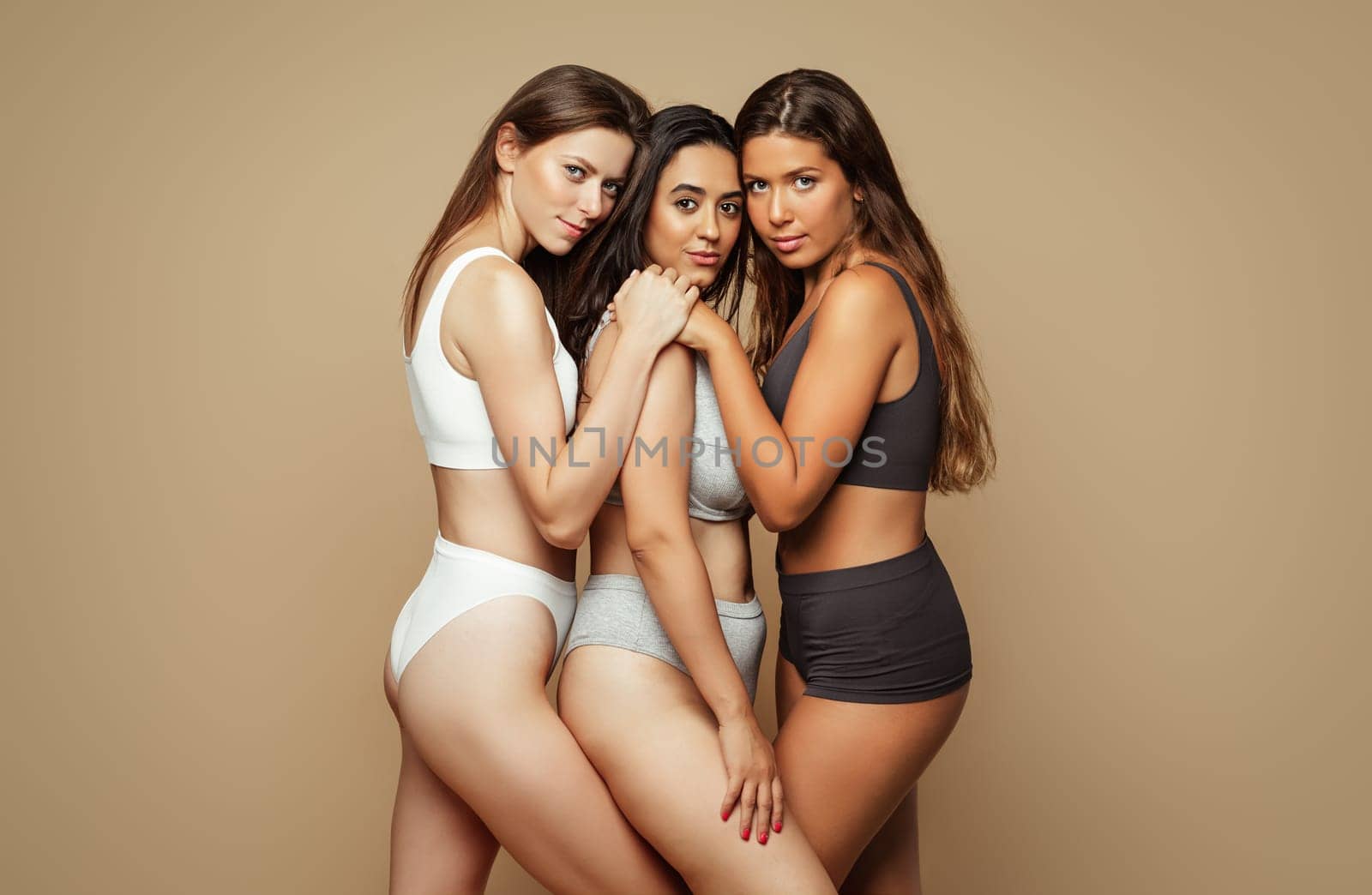 Serious calm pretty group of young international women in different underwear with natural beauty, isolated on beige background, studio. Female power, health care and feminism