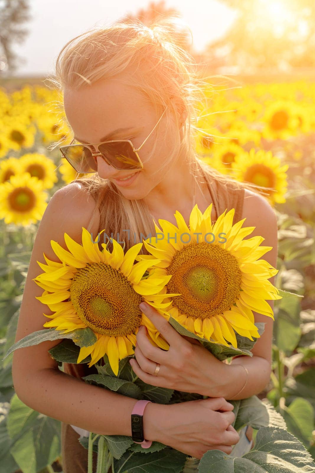 Beautiful woman in sunflower field at sunset enjoying summer nature. Attractive blonde with long healthy hair