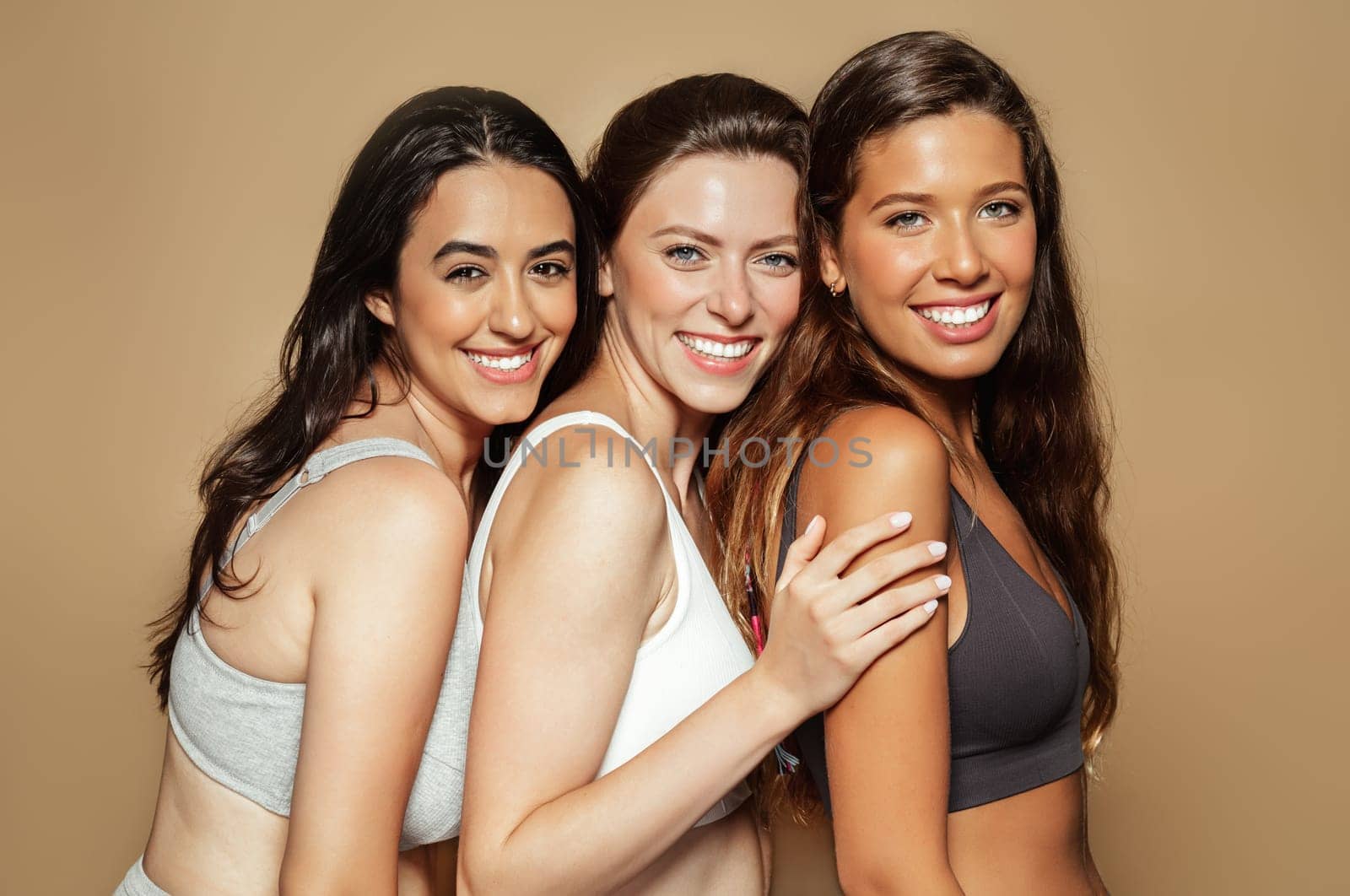 Happy young arabic, latin and european women in different underwear enjoy free time, natural beauty, isolated on beige background, studio. Lifestyle, health care, freshness