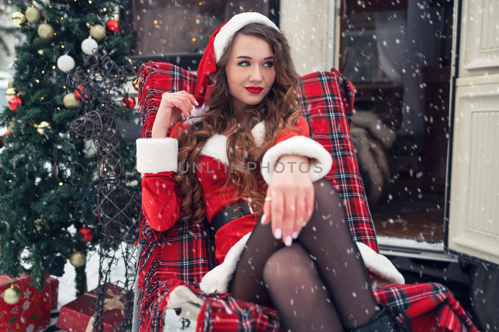 Young woman in santa costume resting at winter campsite. New year celebration concept