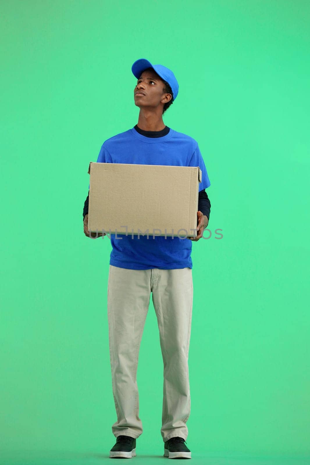 The deliveryman, full-length, on a green background, with a box.