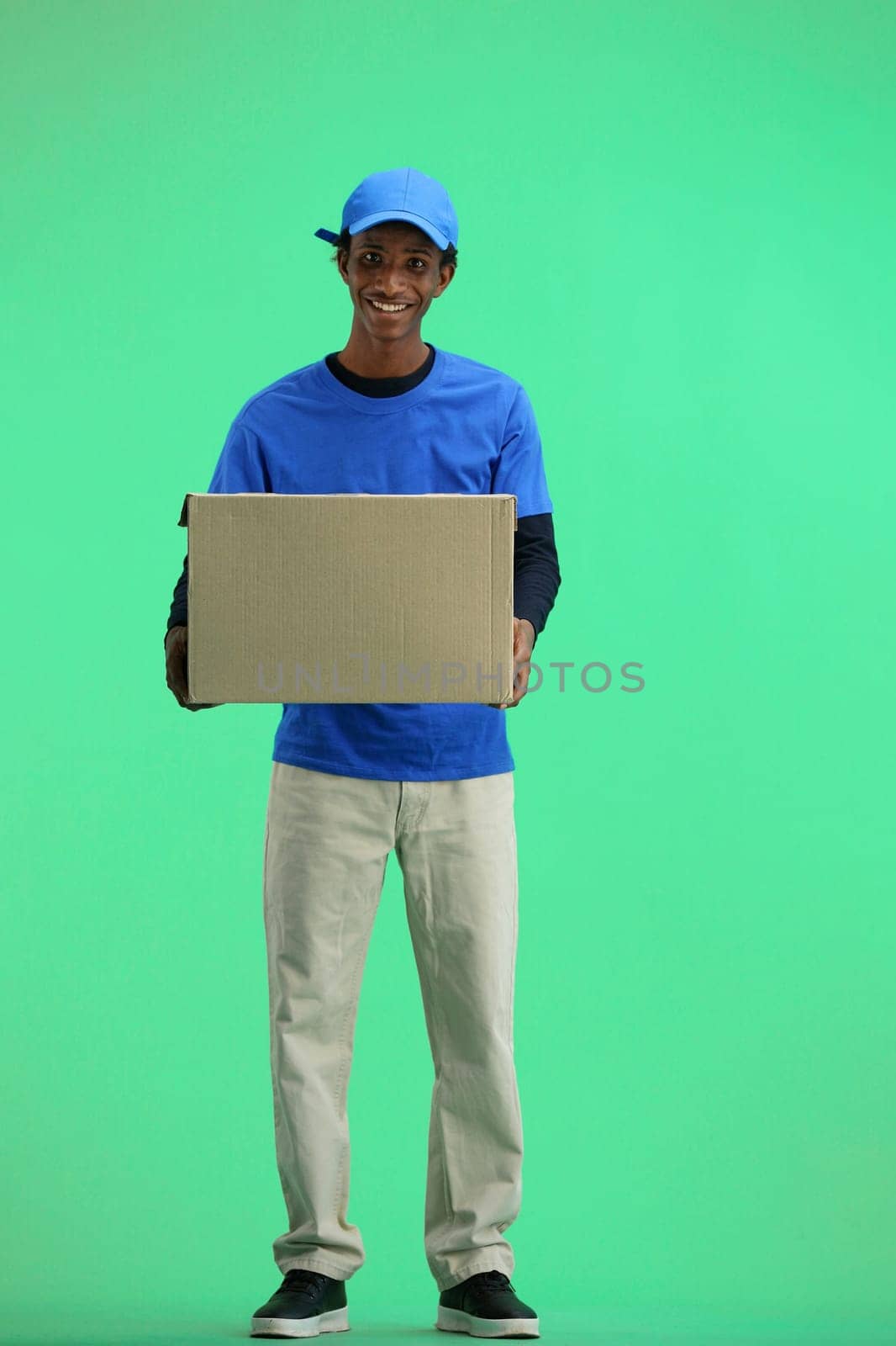 The deliveryman, full-length, on a green background, with a box.