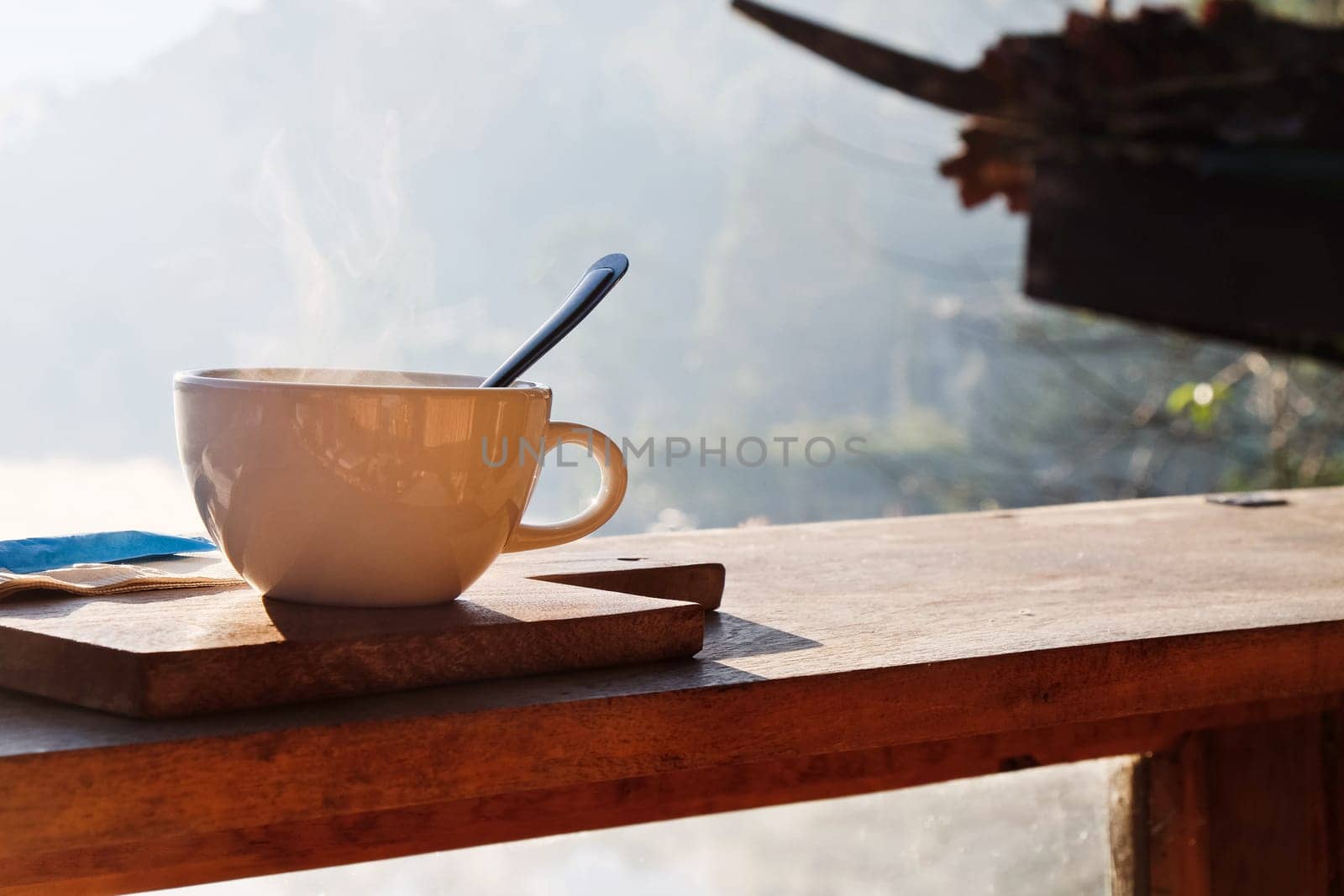 Coffee cup on wooden table with morning fog and mountain background