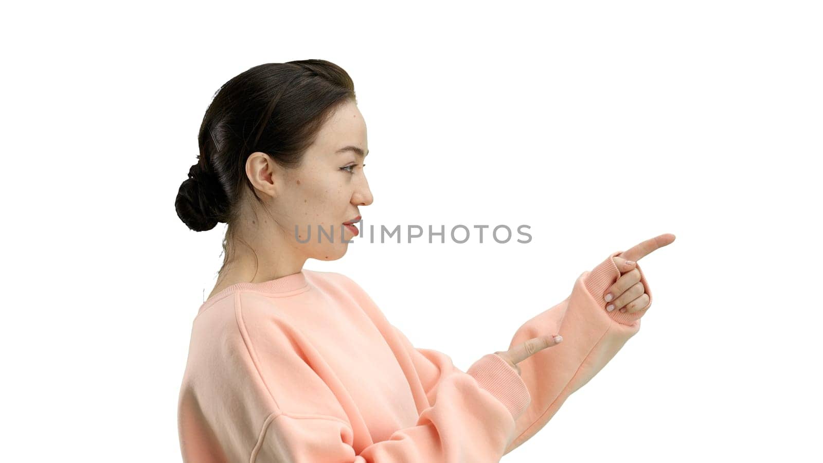 A woman, close-up, on a white background, points to the side.