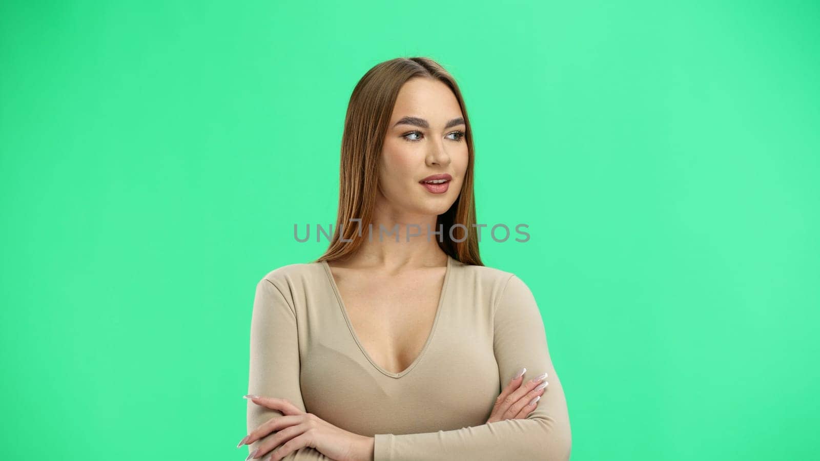 A woman, close-up, on a green background, crossed her arms.