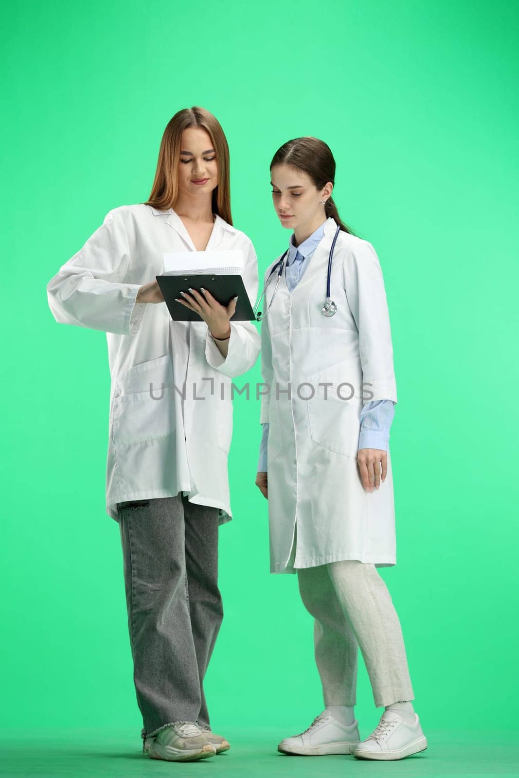 Female doctors, full-length, on a green background, talking by Prosto