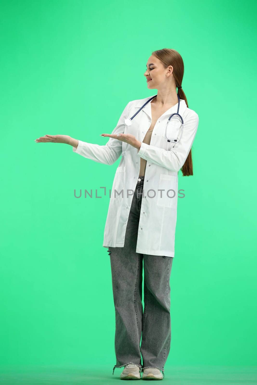 A full-length female doctor, on a green background, points to the side.