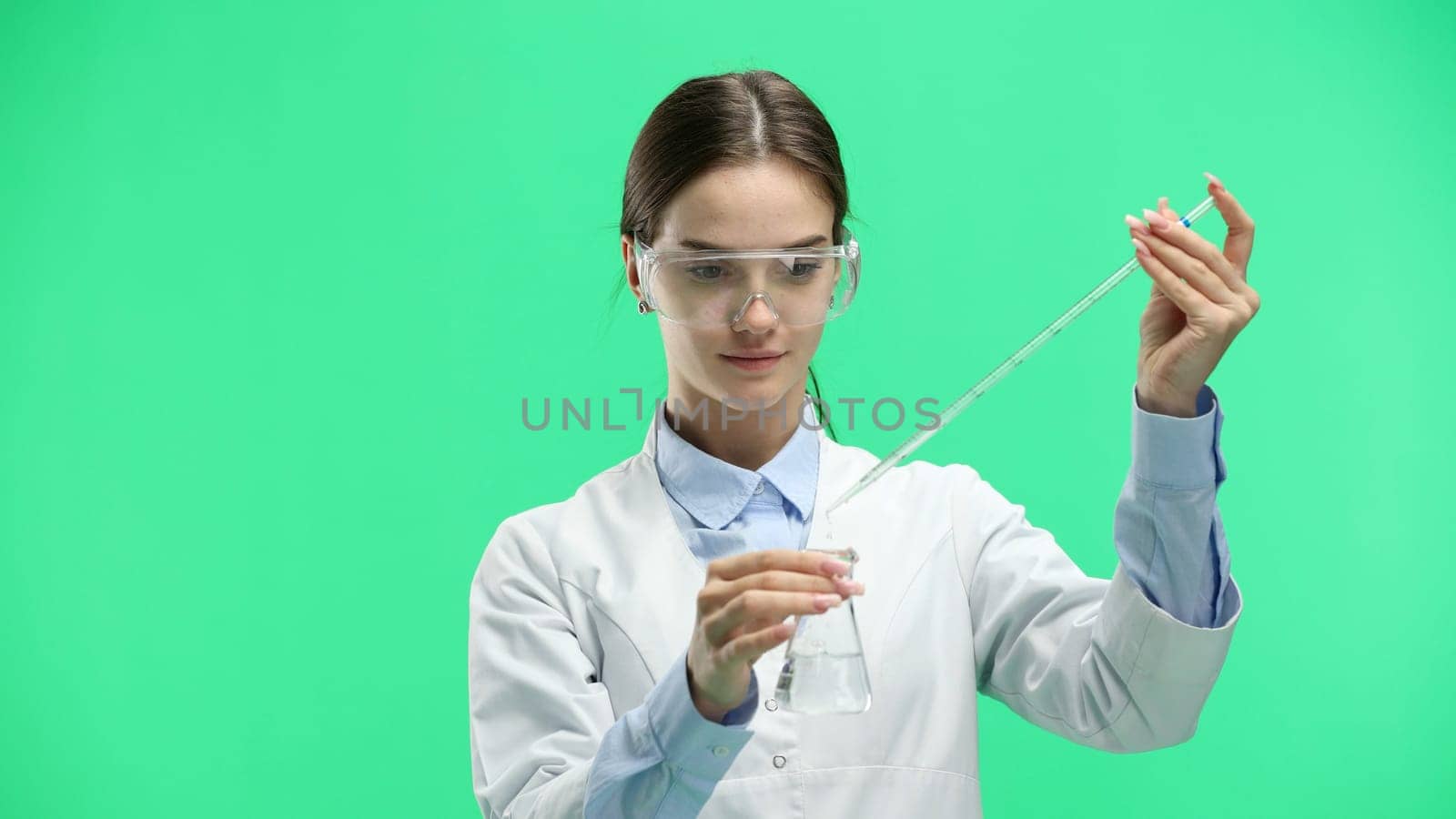 Female doctor, close-up, on a green background, with an eyedropper.