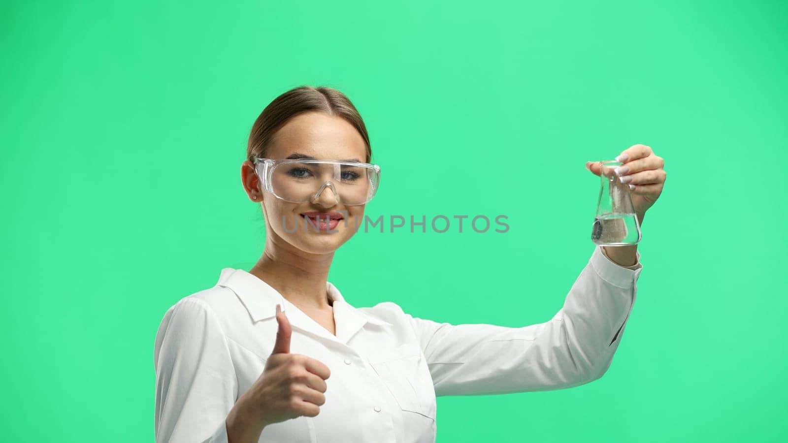 Female doctor, close-up, on a green background, holding a bottle.