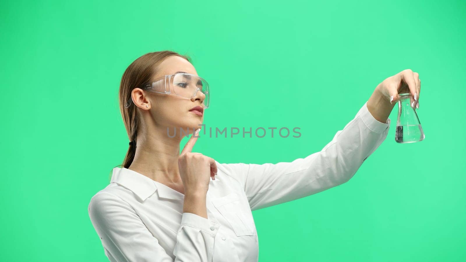 Female doctor, close-up, on a green background, holding a bottle.