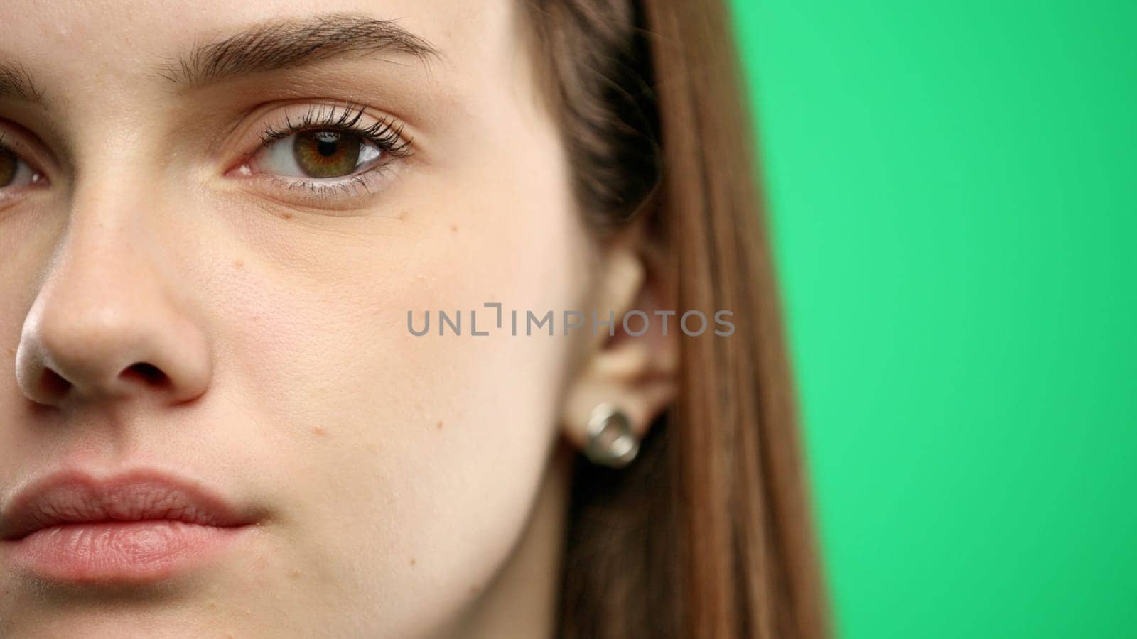 Woman's face, close-up, on a green background.