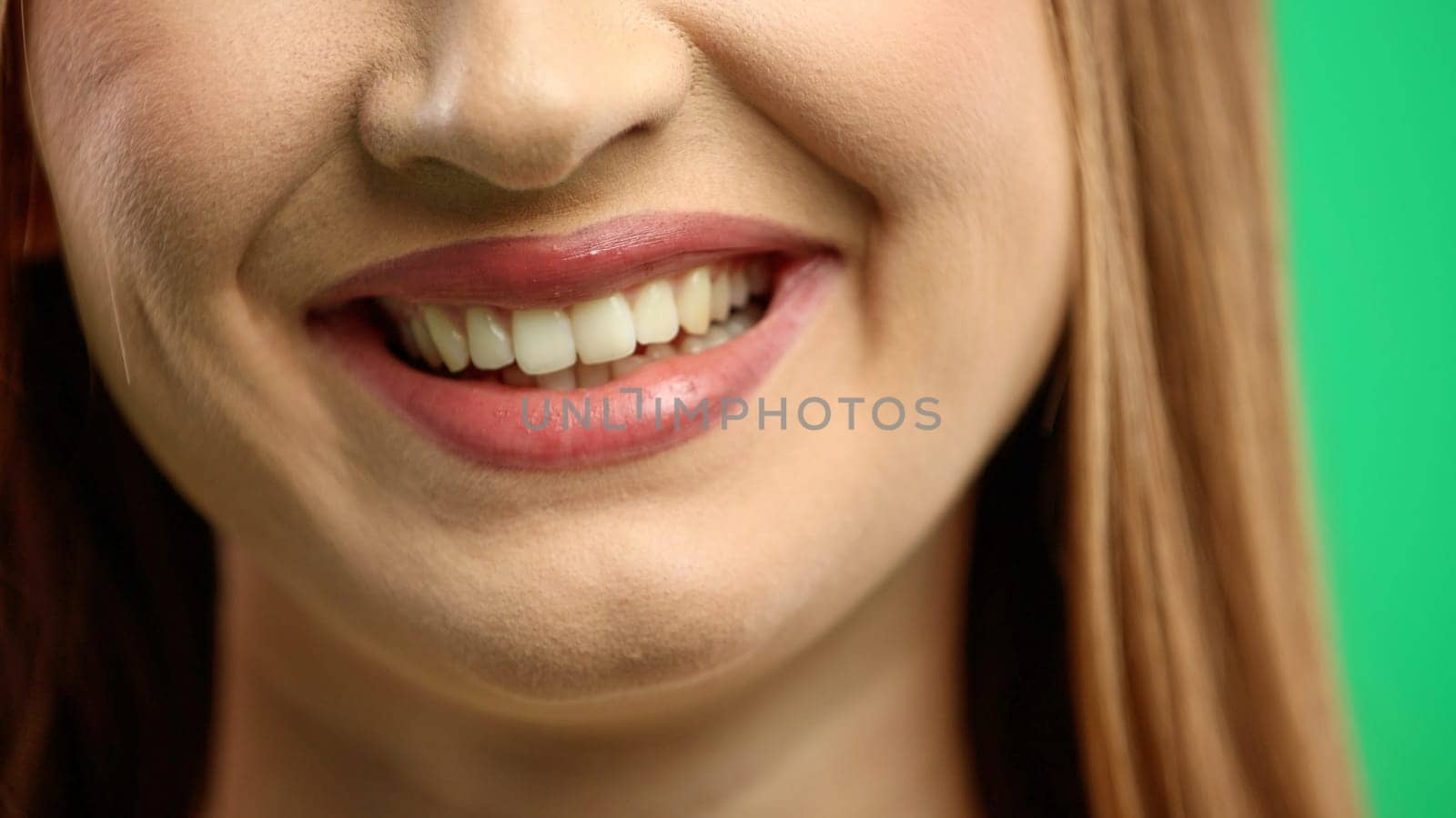 Woman's mouth, close-up, on a green background.