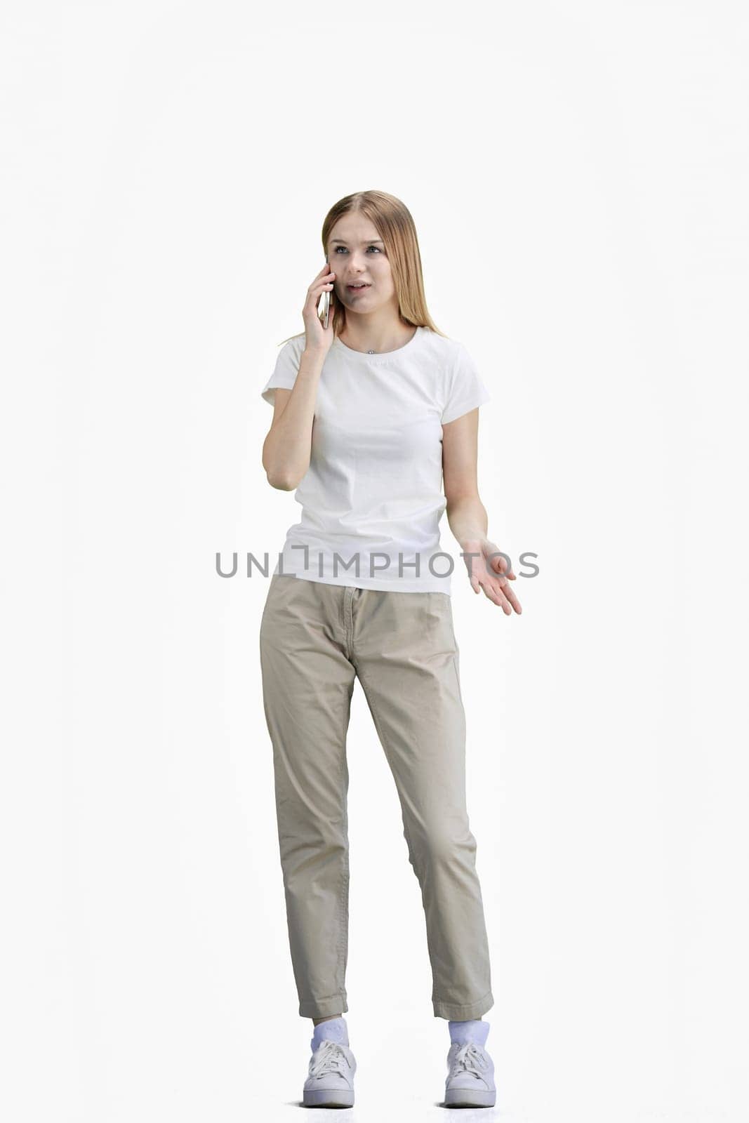 A woman, full-length, on a white background, talking on the phone.