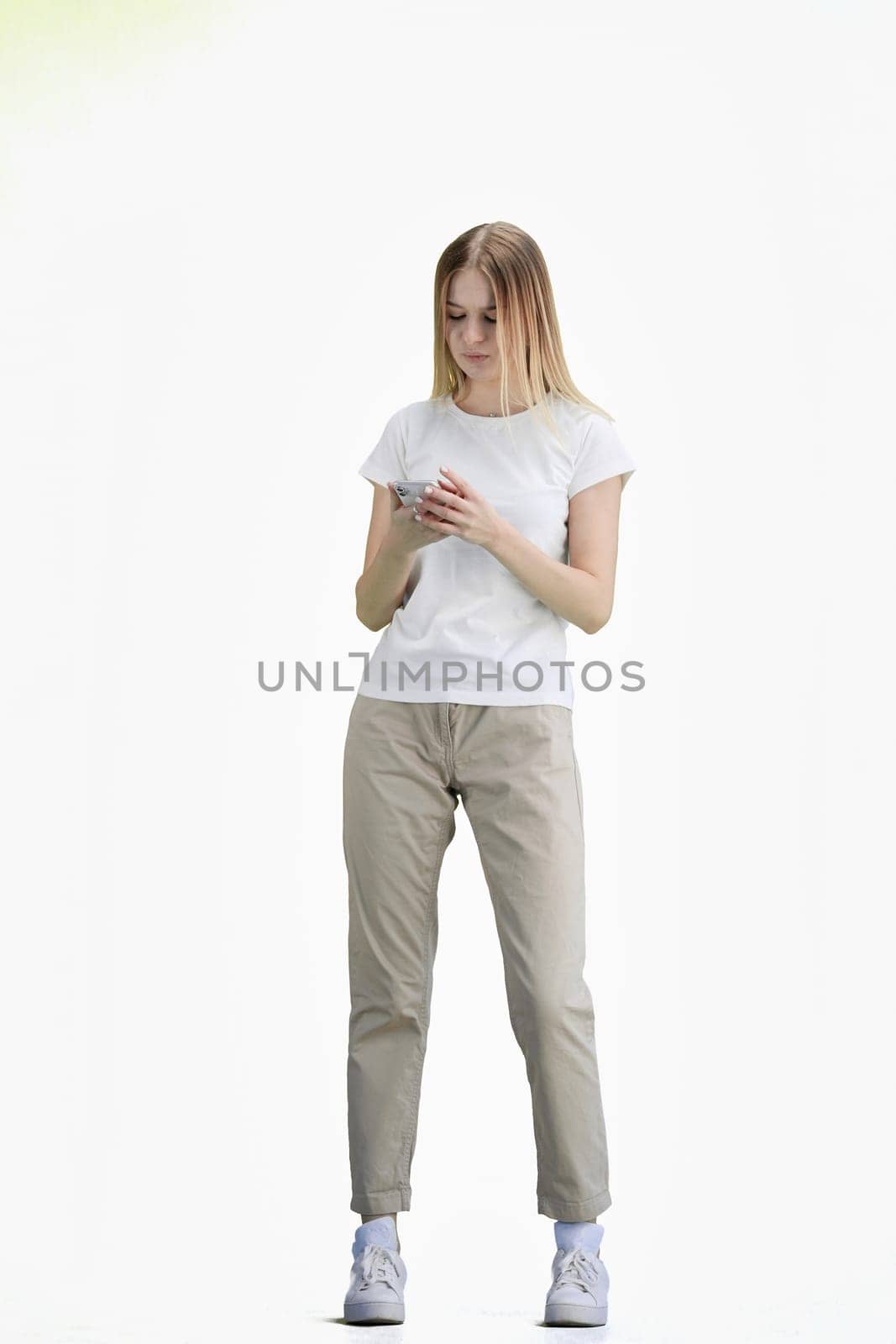 A woman, full-length, on a white background, uses a phone.