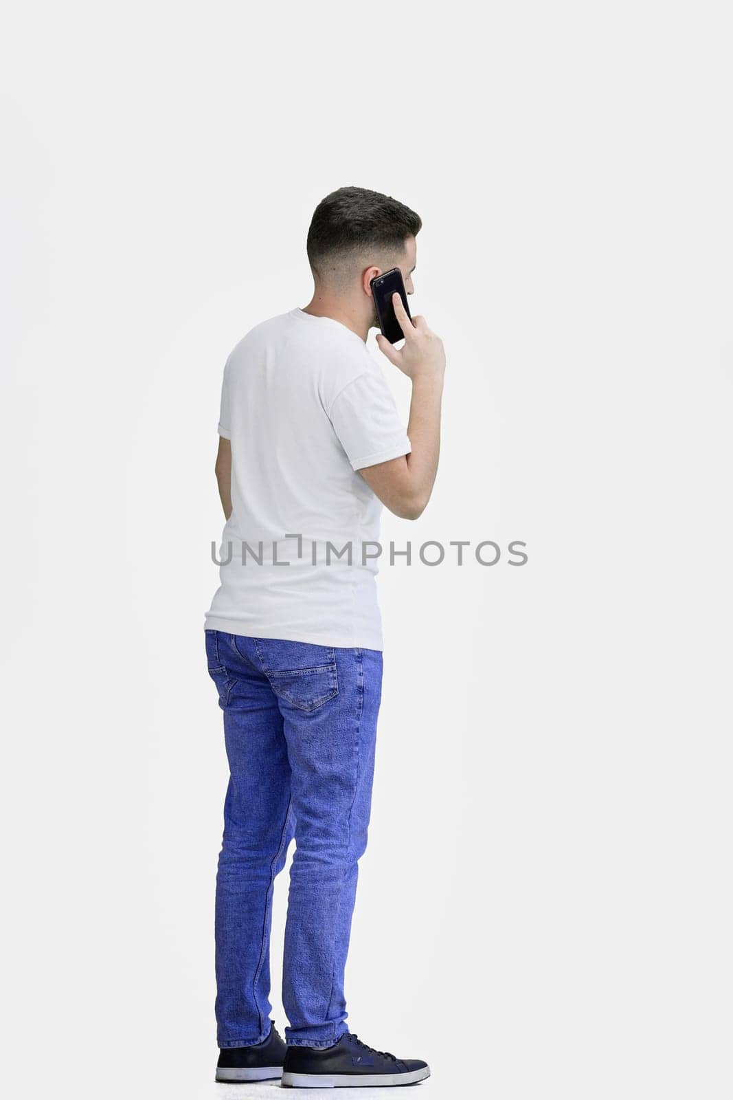 A man, full-length, on a white background, talking on the phone.