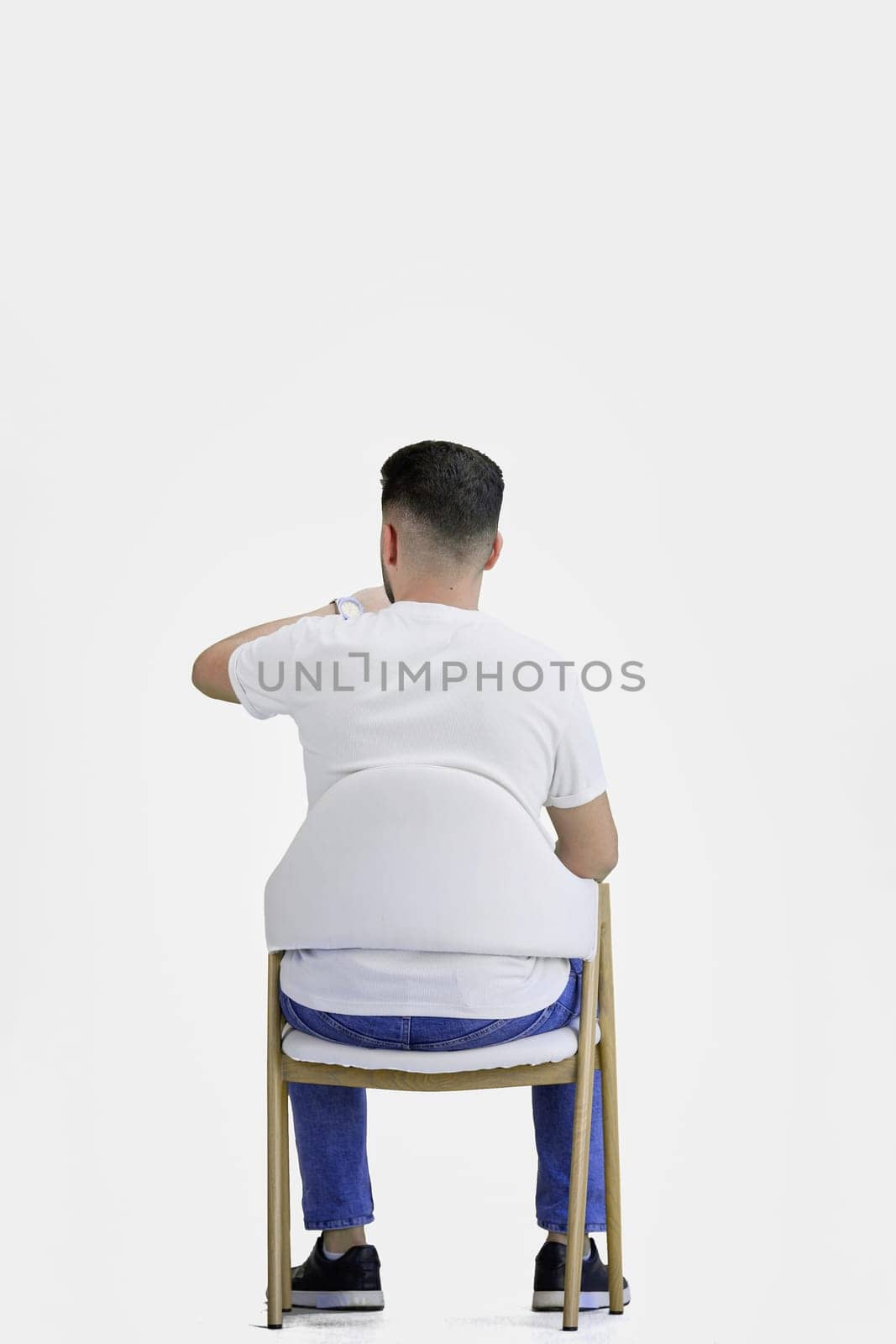 A man, full-length, on a white background, sitting on a chair.