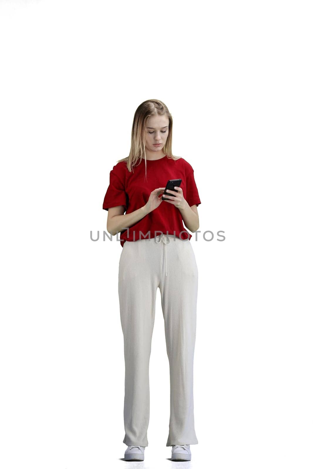 A woman, full-length, on a white background, uses a phone.