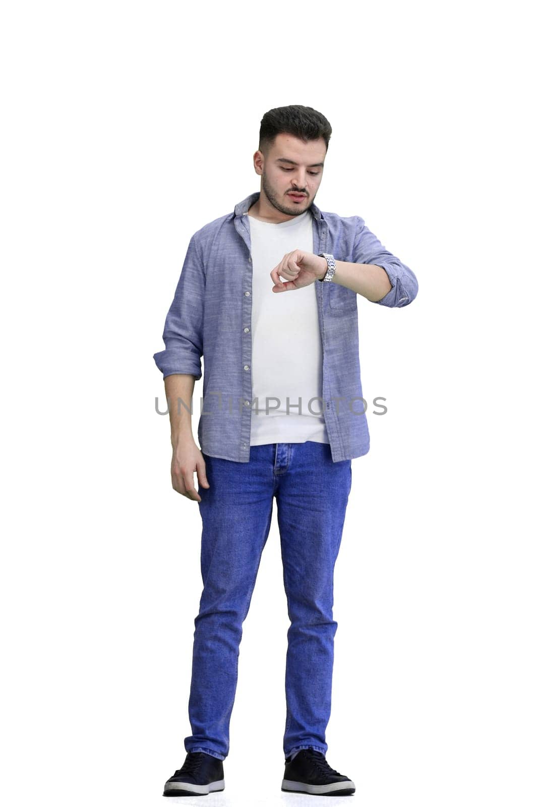 A man, full-length, on a white background, looks at his watch.