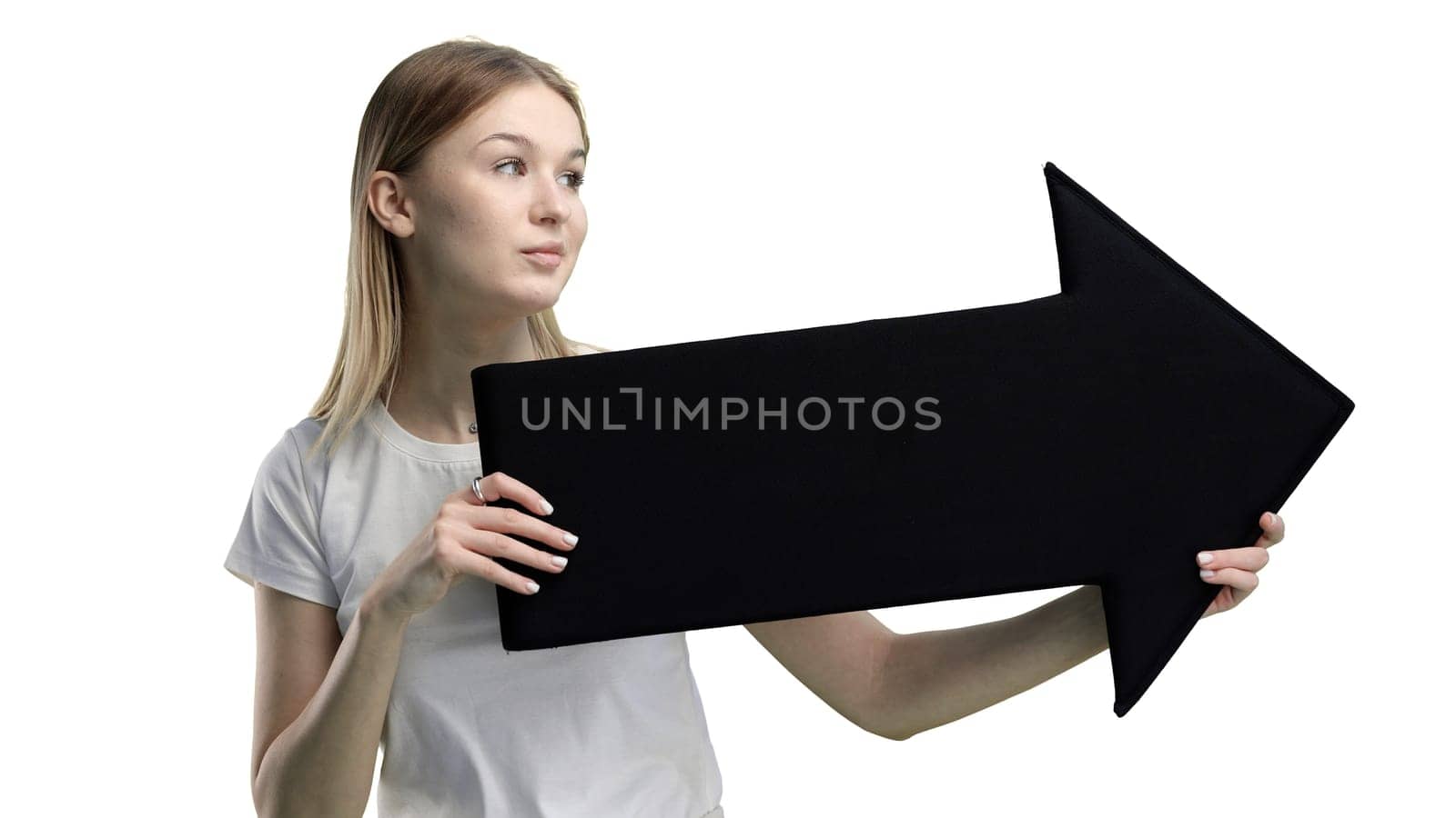 A woman, in close-up, on a white background, points an arrow to the side.