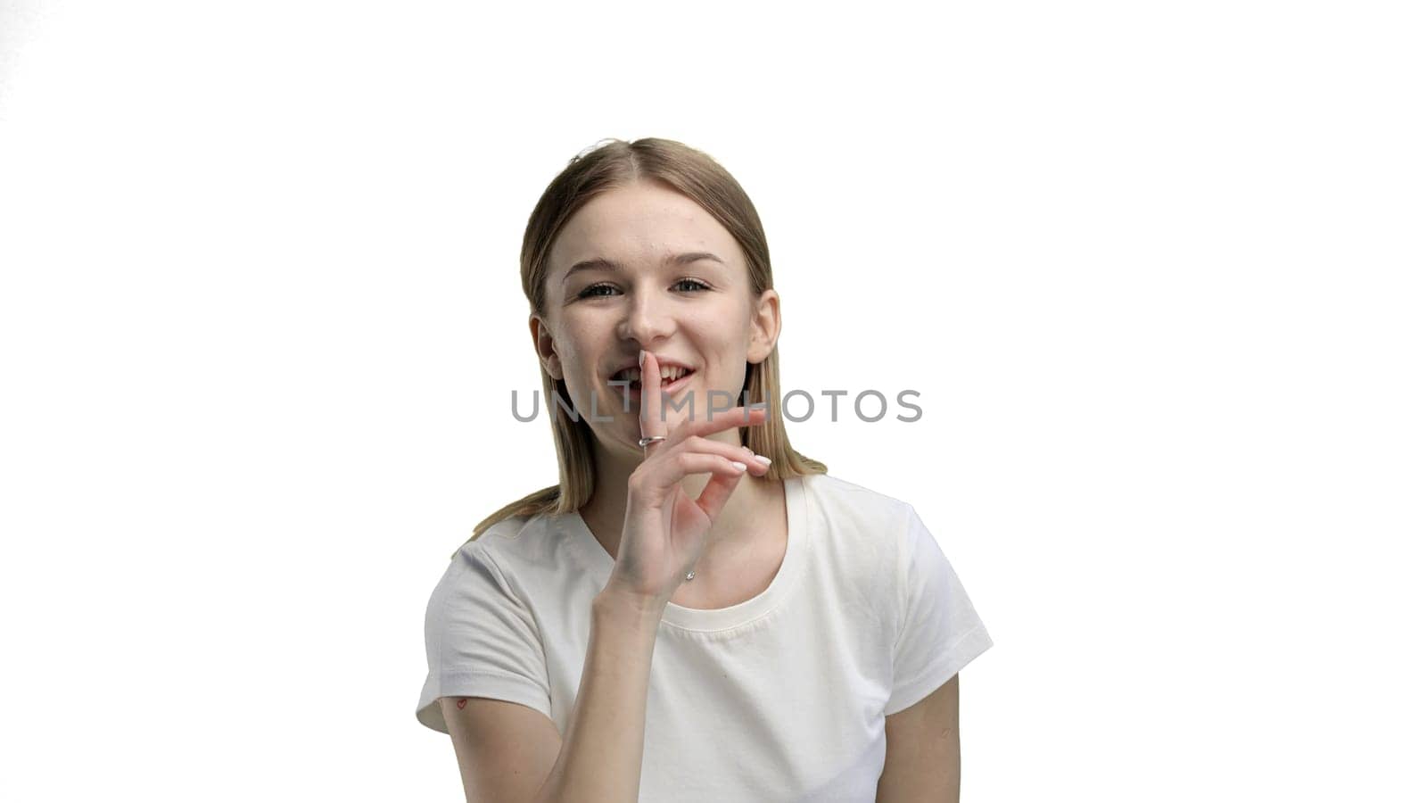 A woman, close-up, on a white background, shows a sign of silence.