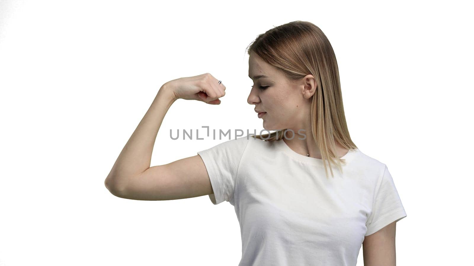 A woman, close-up, on a white background, shows strength.