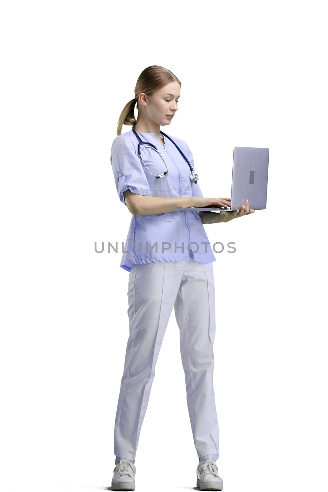 The doctor, in full height, on a white background, uses a laptop.