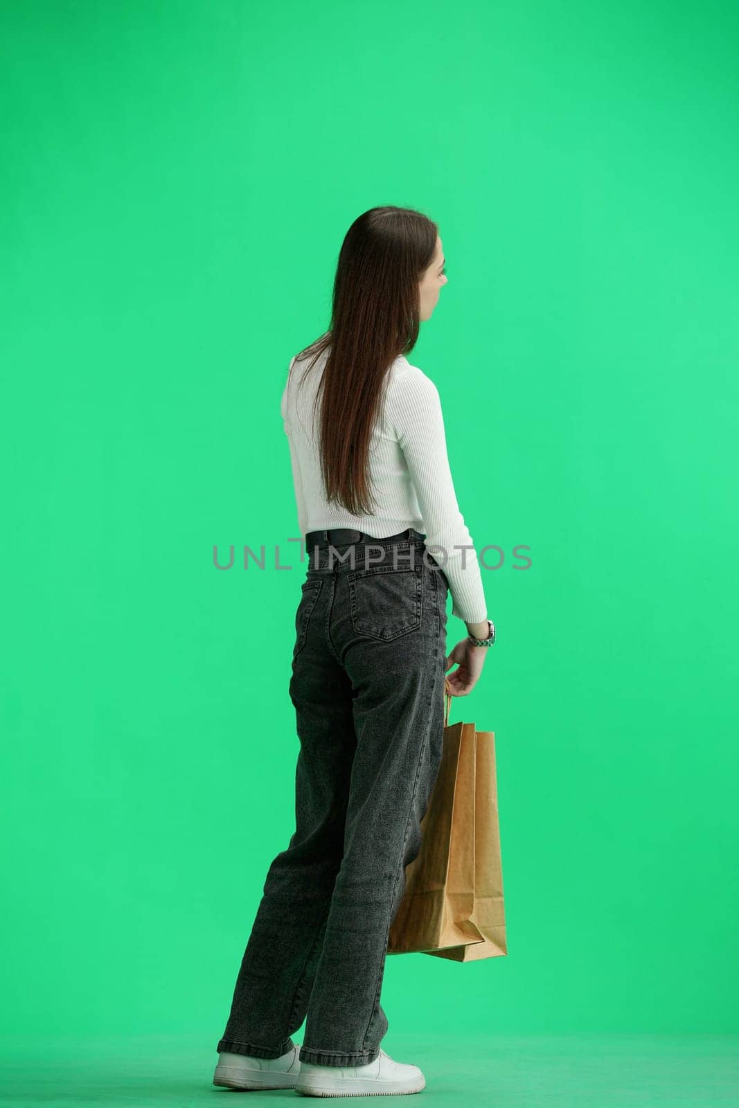 A woman, full-length, on a green background, with bags.