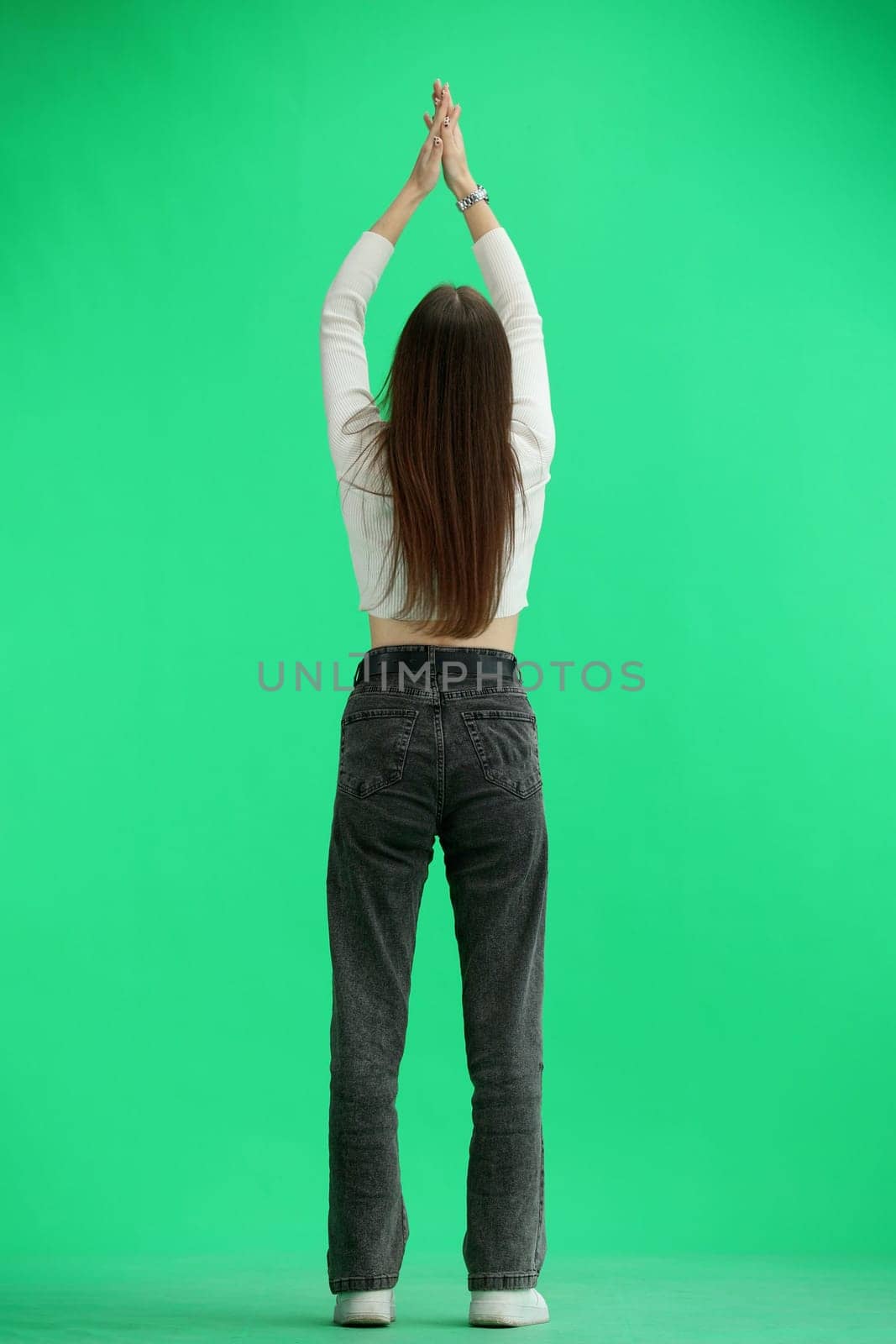 A woman, full-length, on a green background, claps.