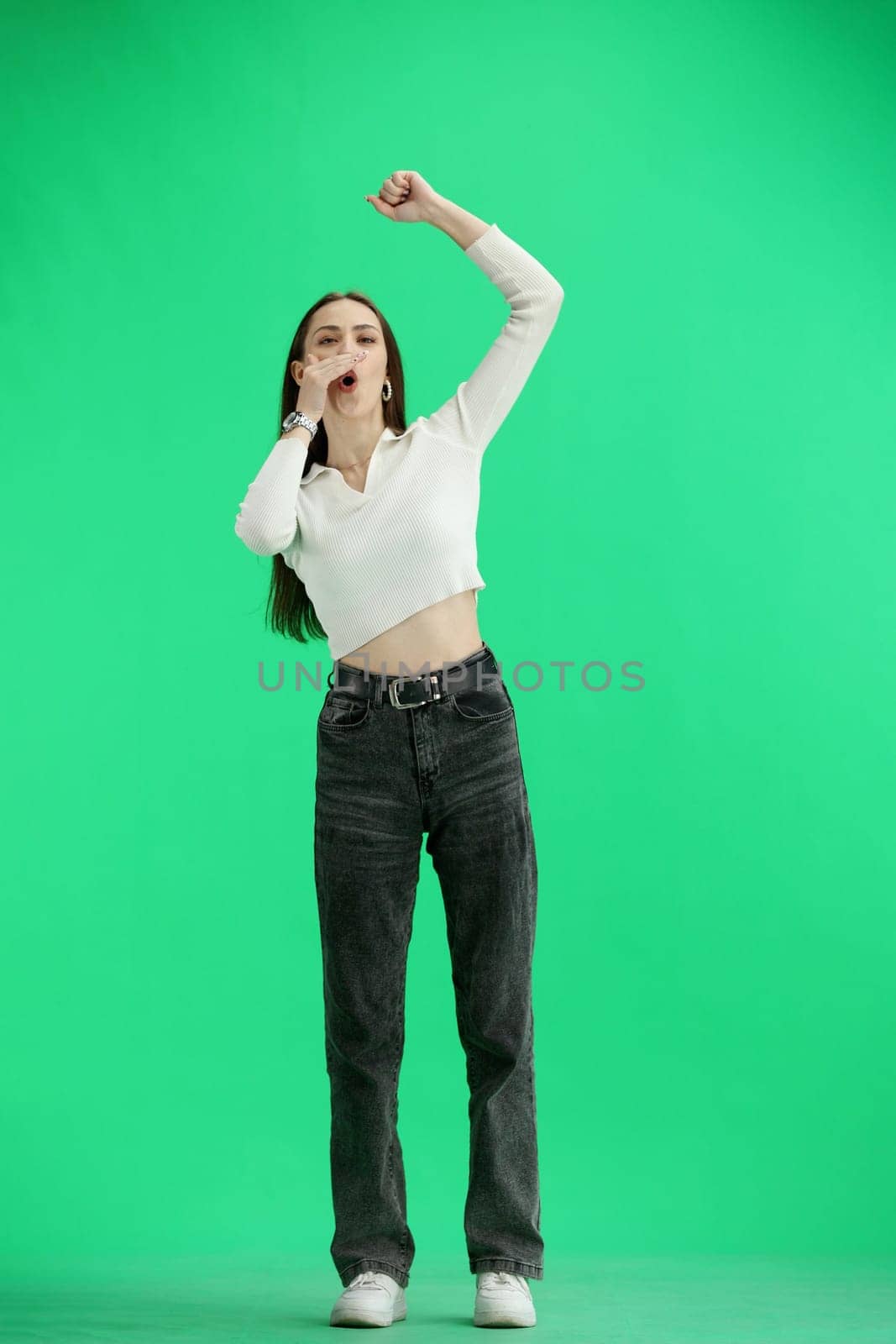 A woman, full-length, on a green background, rejoices.