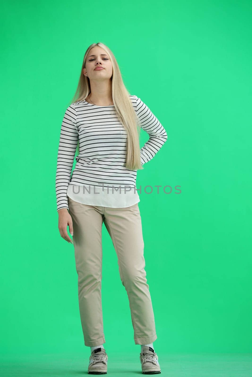 A woman, full-length, on a green background.
