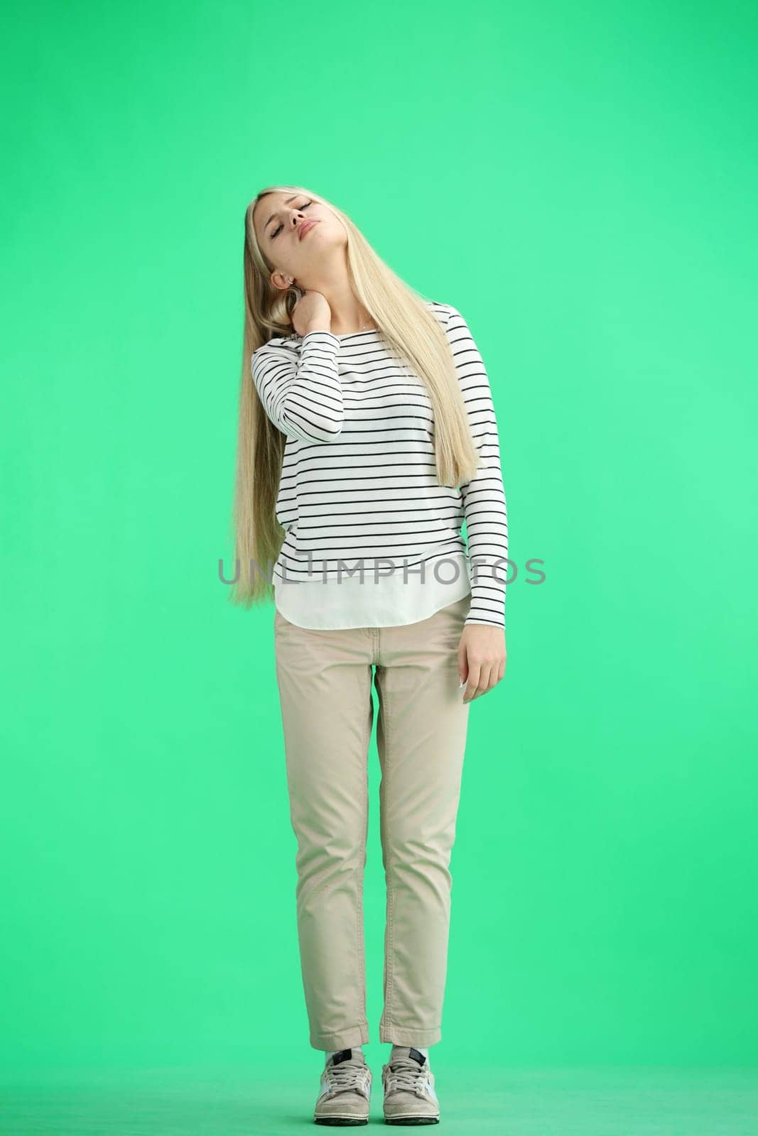 A woman, full-length, on a green background, tired.
