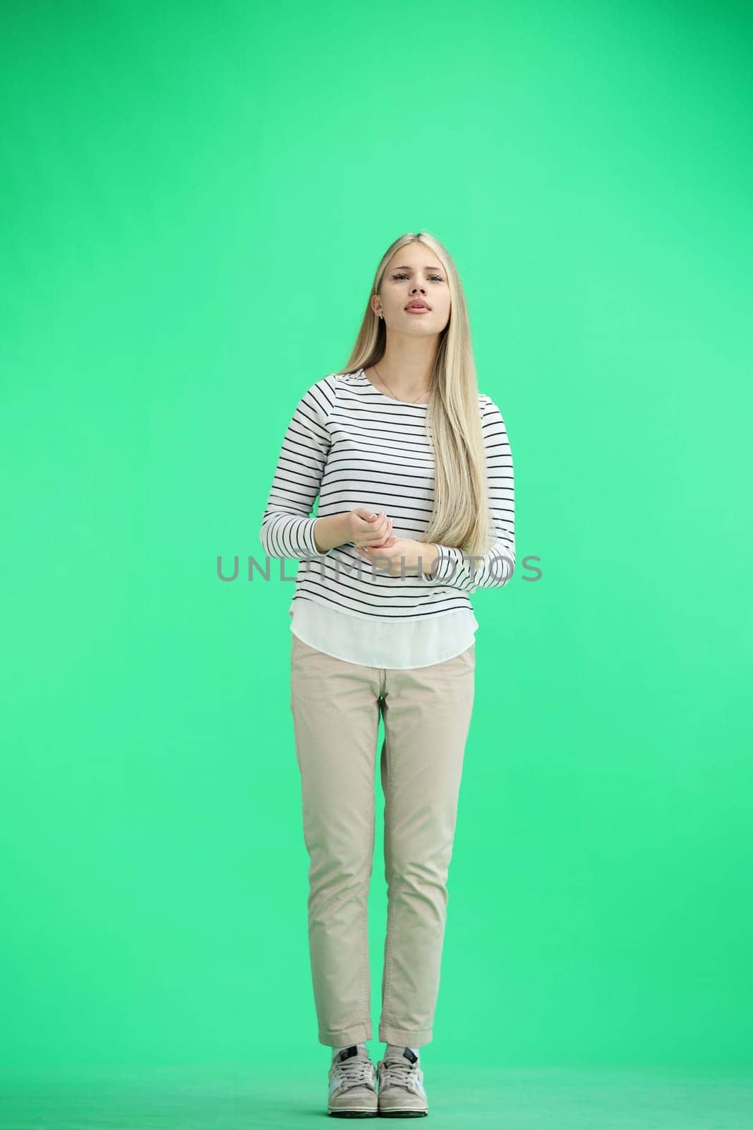 A woman, full-length, on a green background, folded her arms.