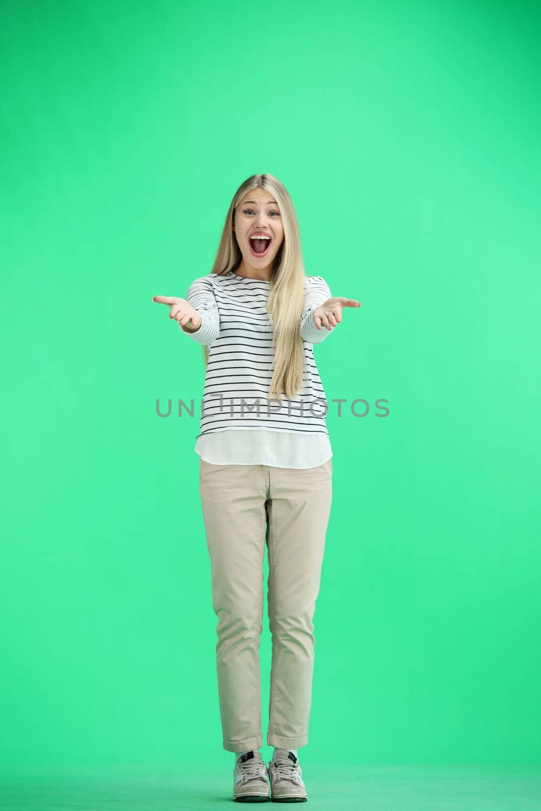 A woman, full-length, on a green background, admires.