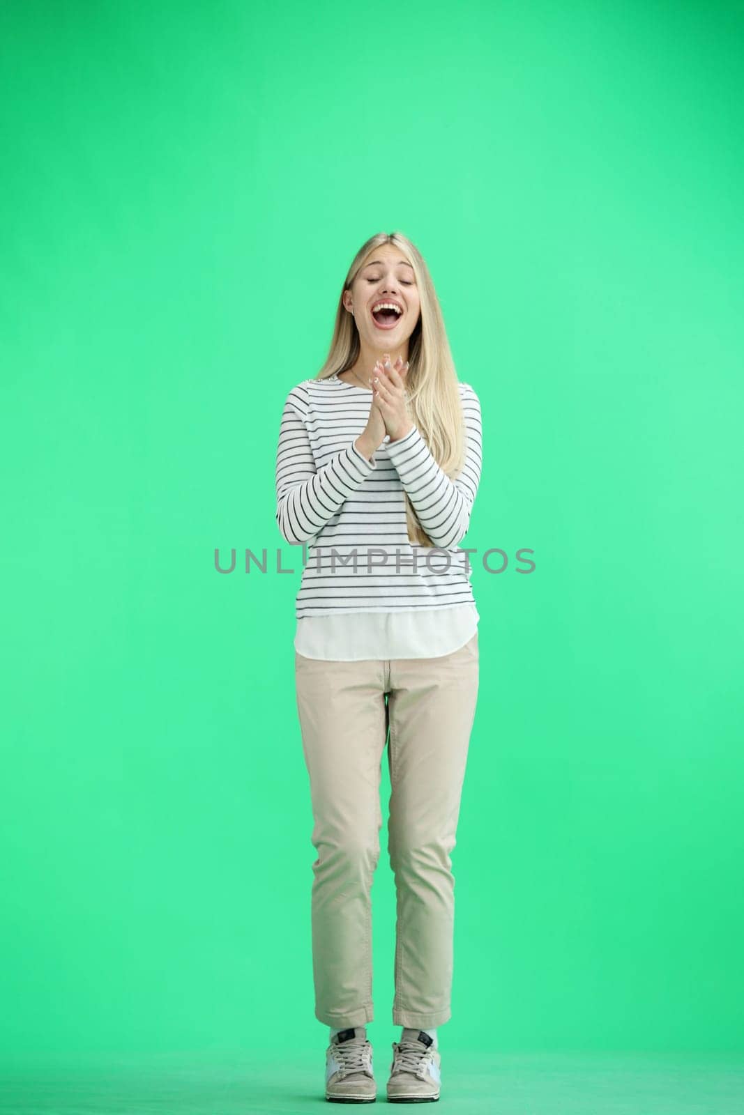 A woman, full-length, on a green background, claps.