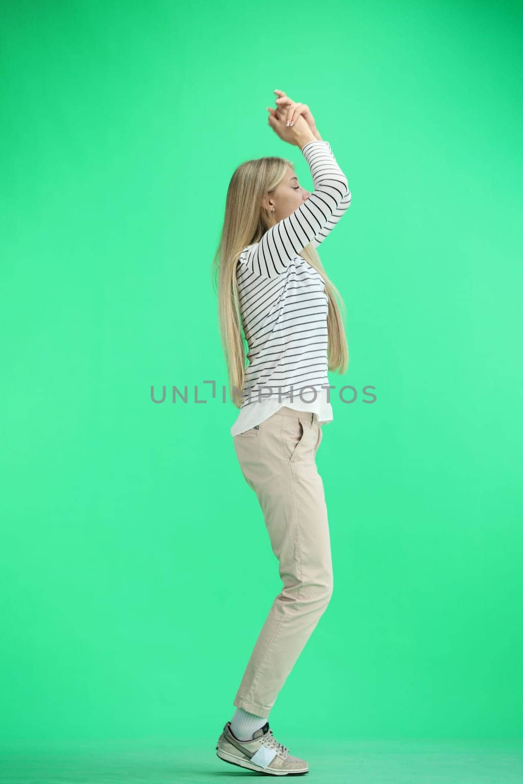 A woman, full-length, on a green background, claps.