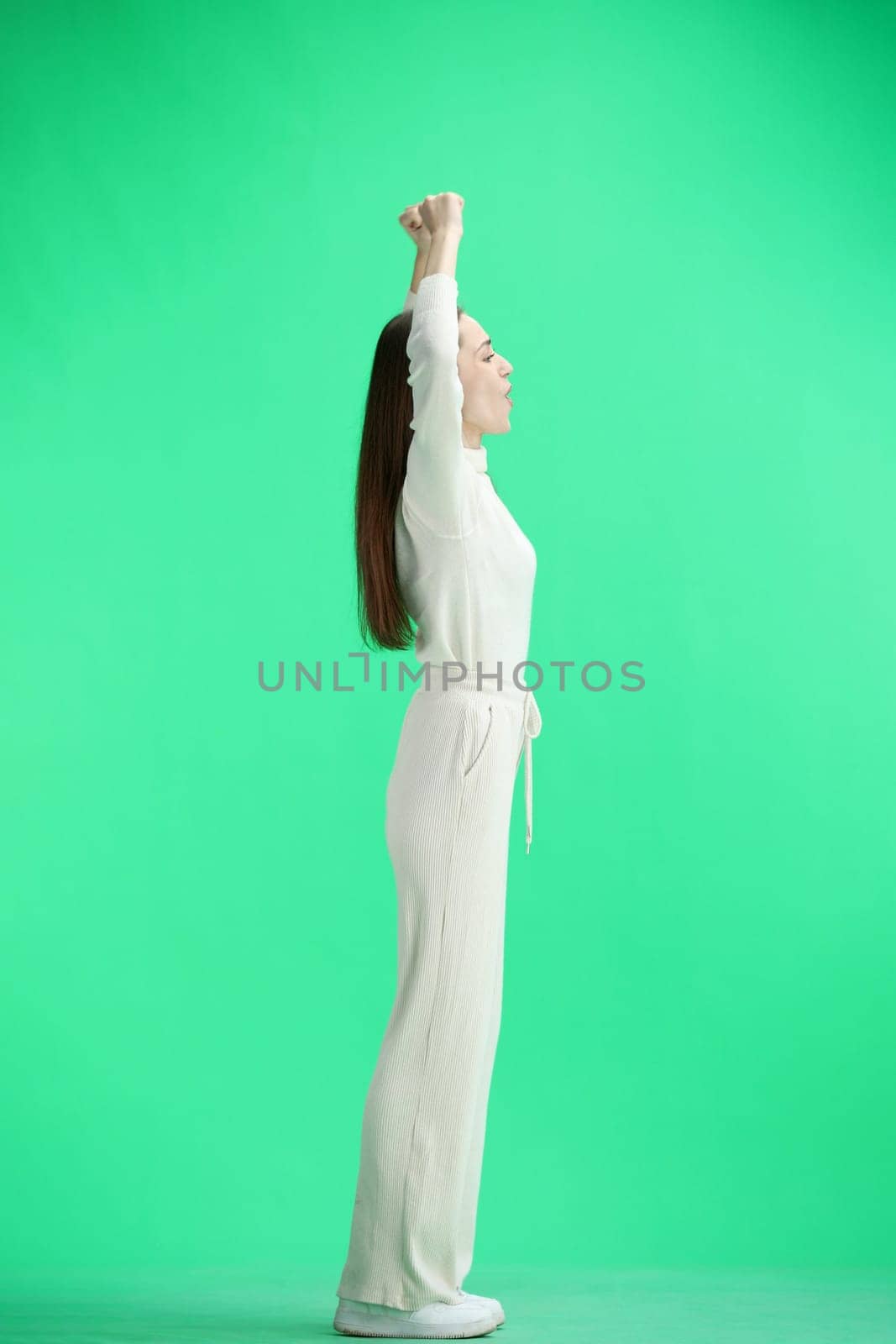 A woman, full-length, on a green background, rejoices.