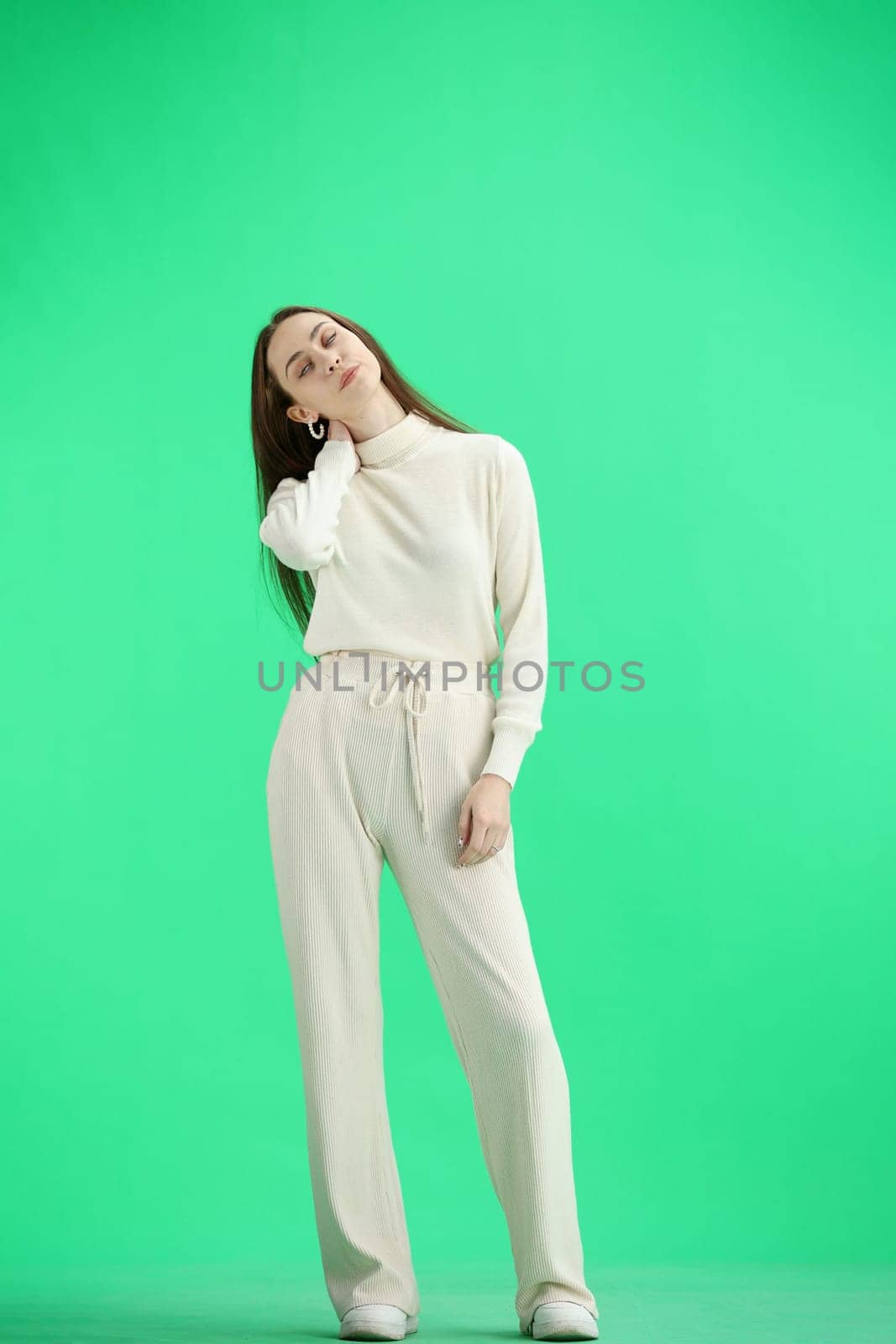 A woman, full-length, on a green background, tired.