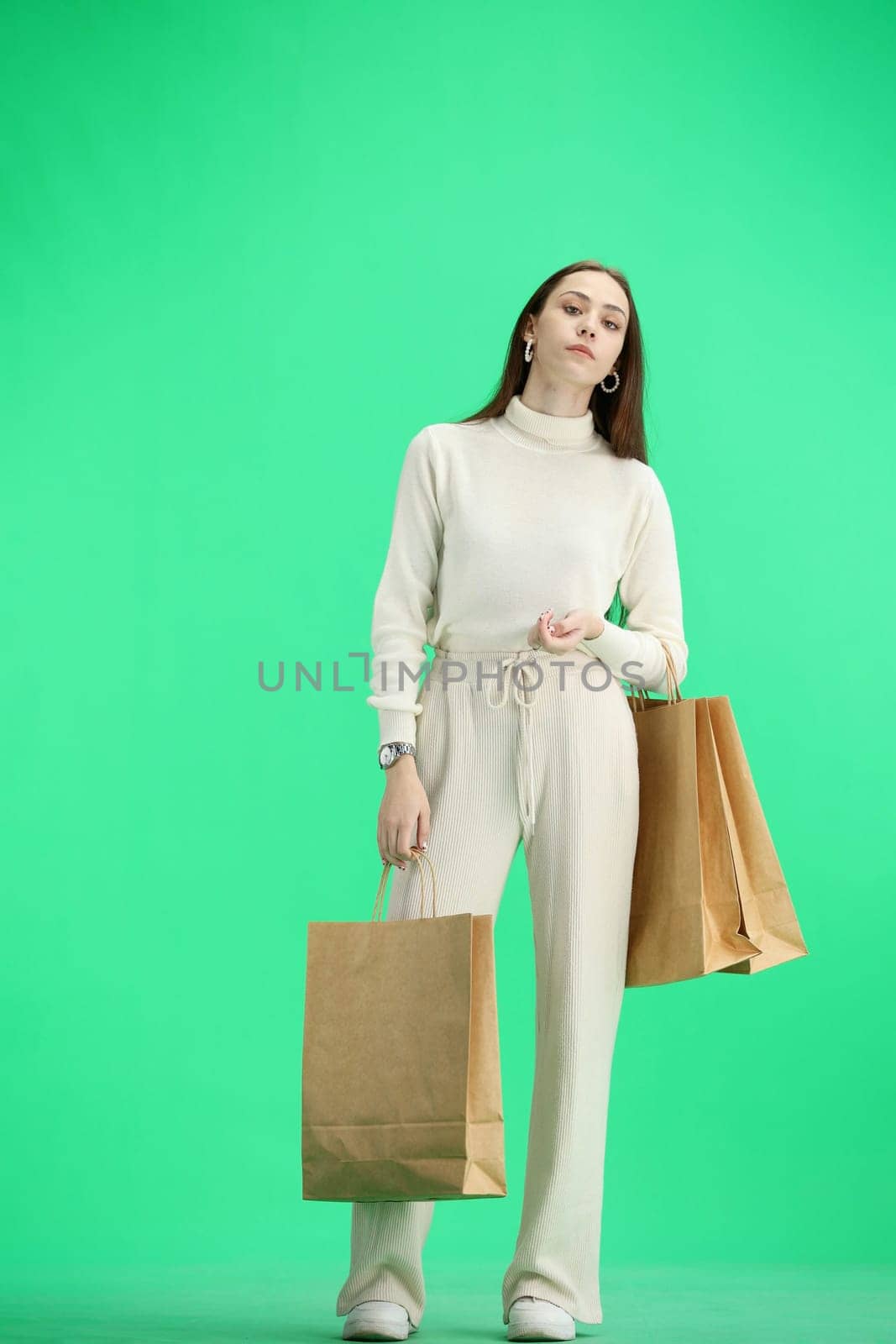 A woman, full-length, on a green background, with bags.