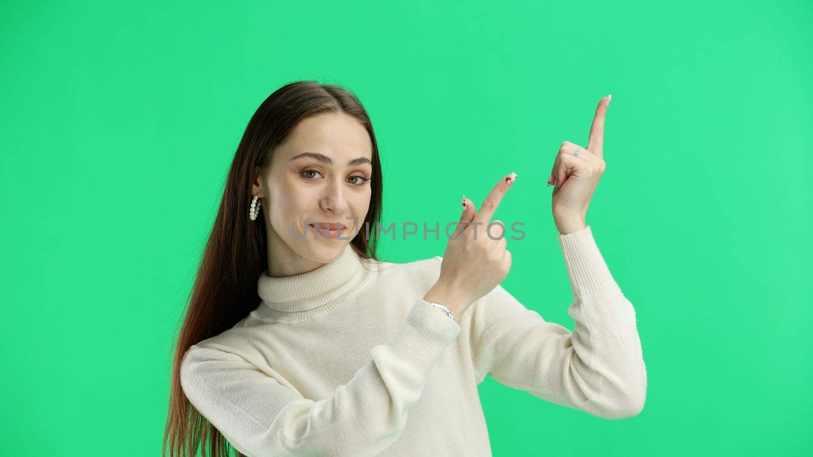 Woman, close-up, on a green background, pointing up.