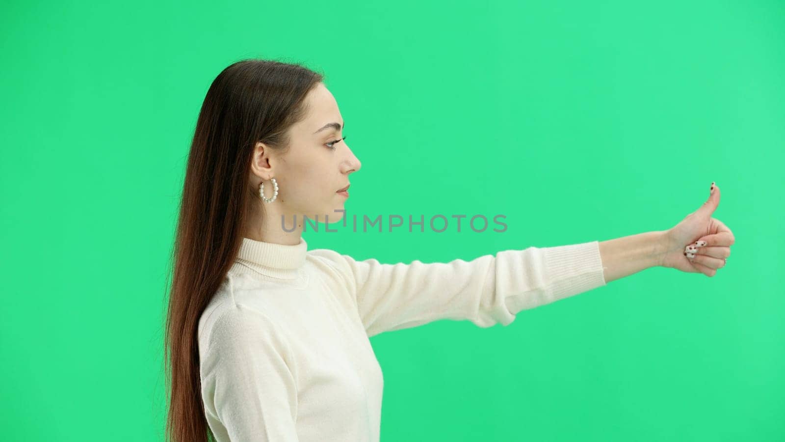 A woman, close-up, on a green background, shows her thumbs up by Prosto