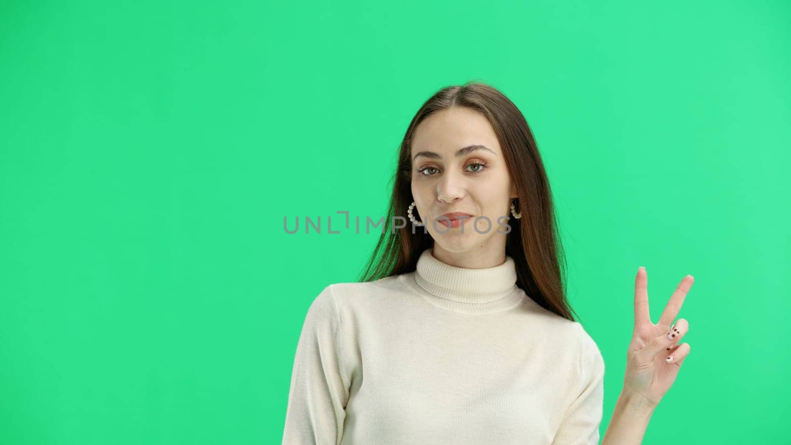 A woman, close-up, on a green background, shows a victory sign by Prosto