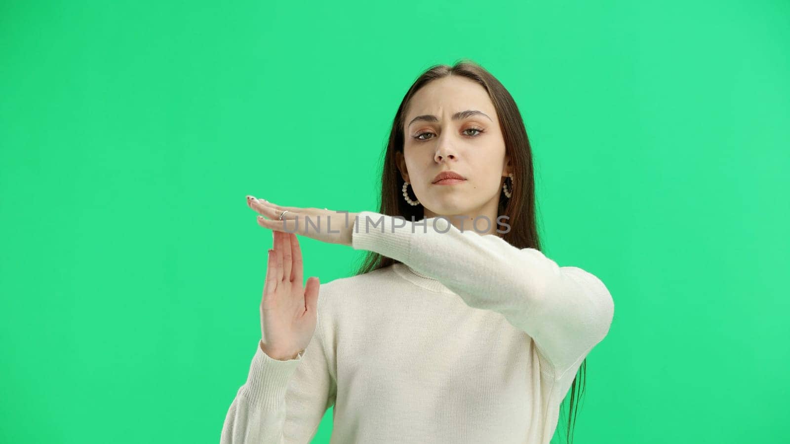 Woman, close-up, on a green background, showing a pause sign.