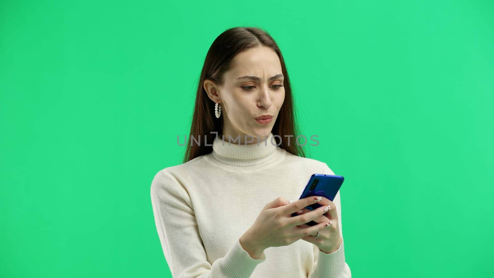 A woman, close-up, on a green background, shows a phone.