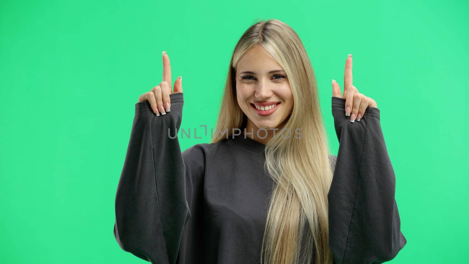 Woman, close-up, on a green background, pointing up.