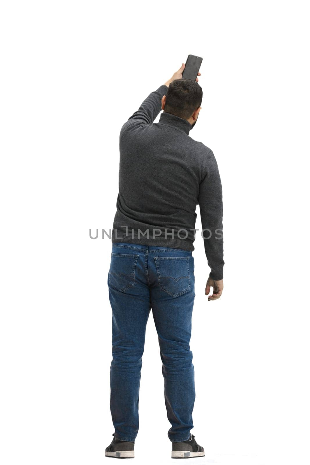 A man, full-length, on a white background, waving his phone.