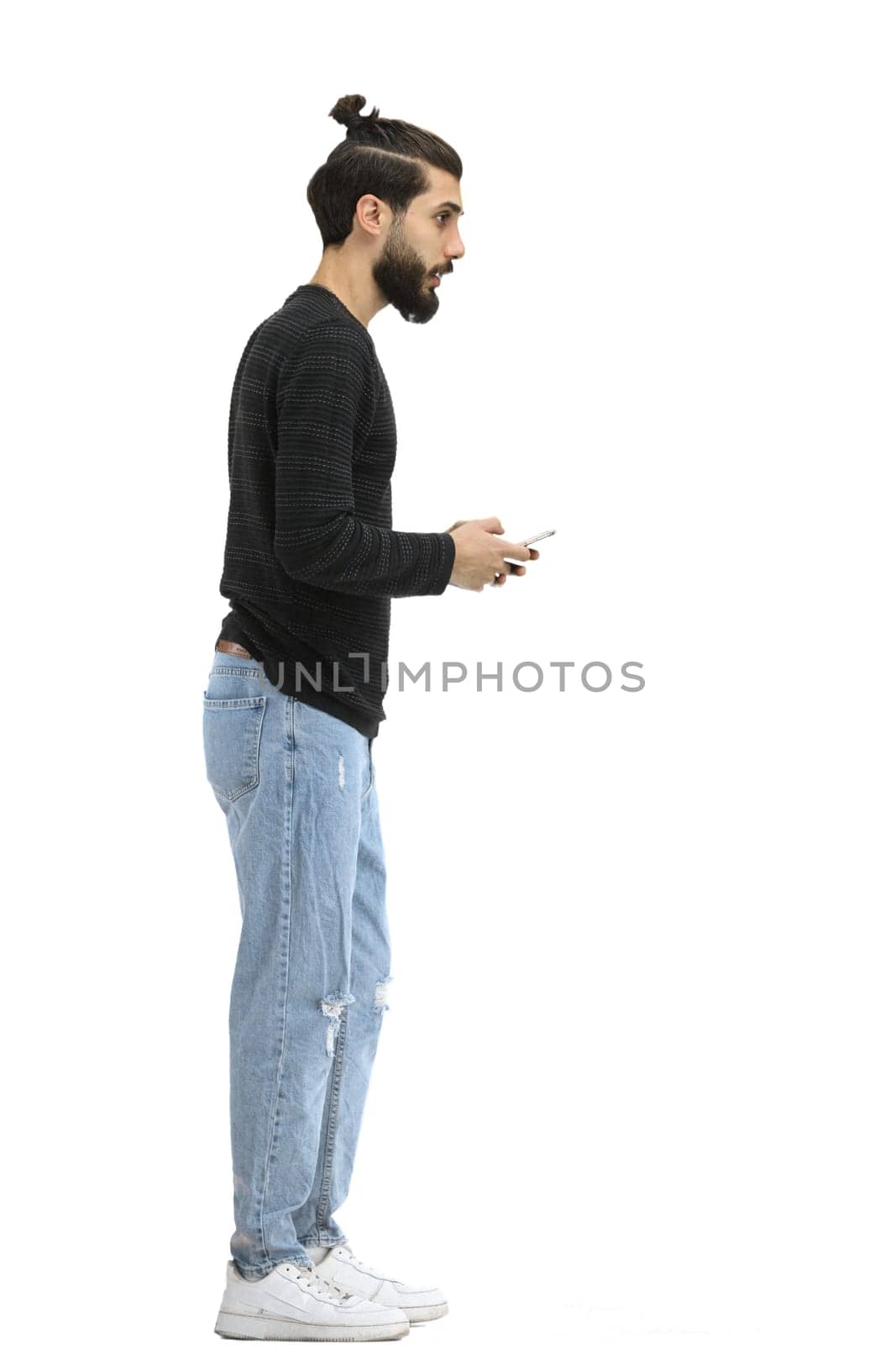 A man, full-length, on a white background, with phone.