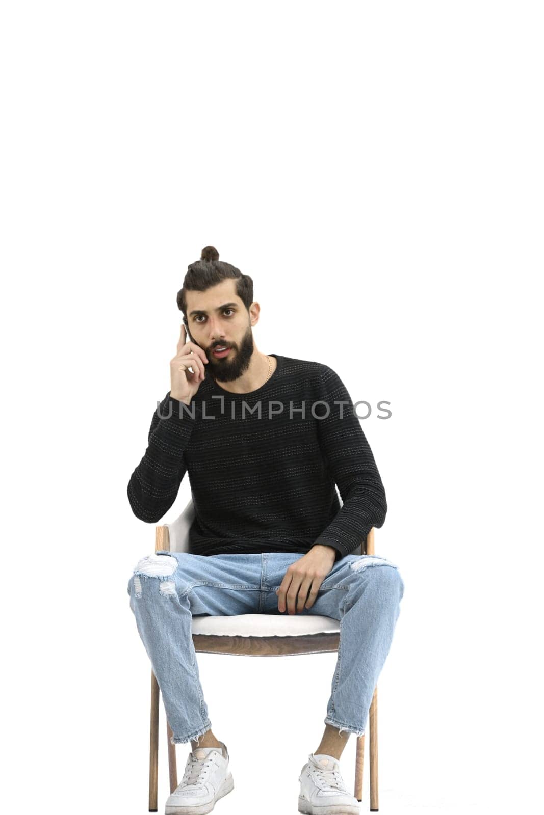 A man, full-length, on a white background, sitting on a chair.