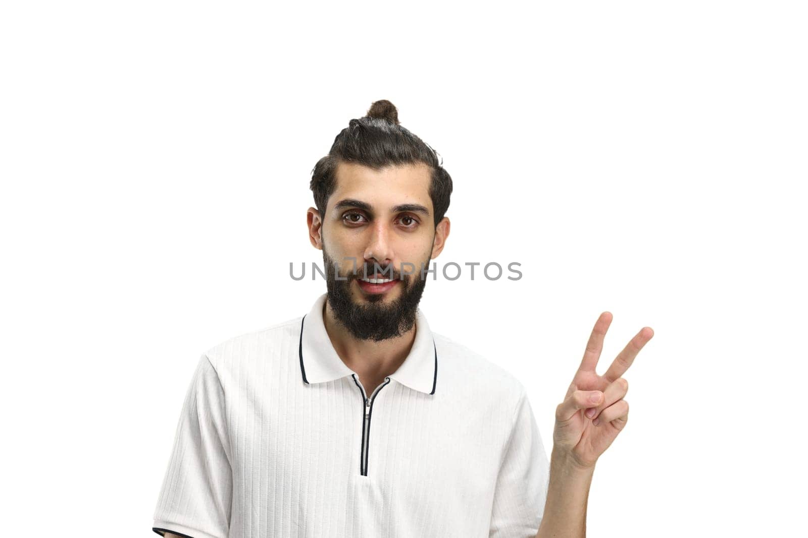 A man, close-up, on a white background, shows a victory sign.
