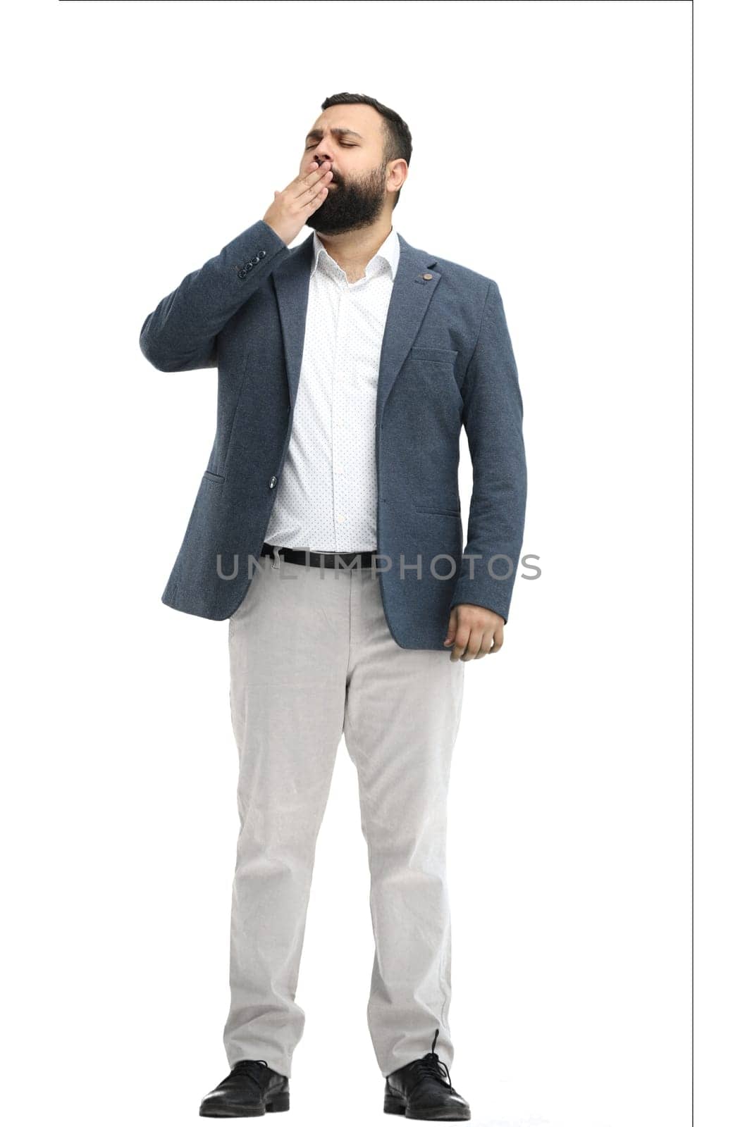 A man, full-length, on a white background, yawns.