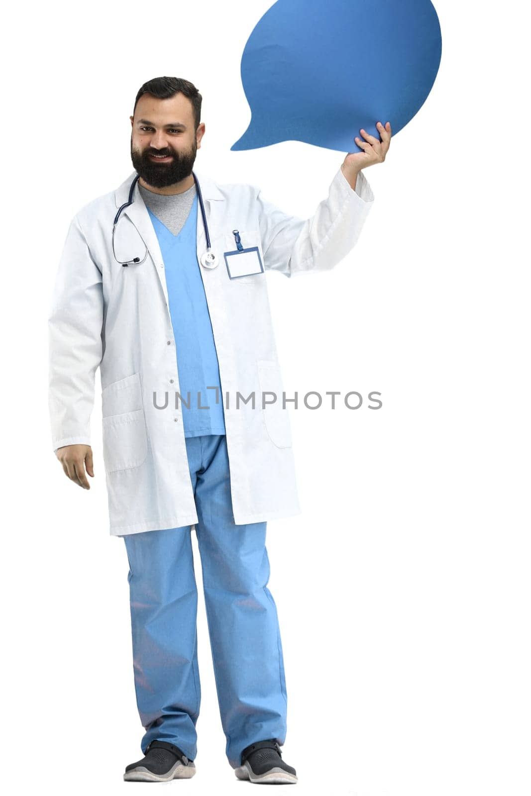 Male doctor, full-length, on a white background, shows a blue comment sign.
